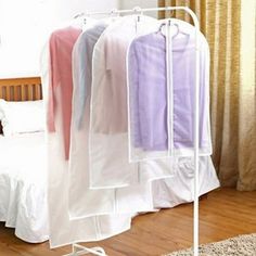 a rack with clothes hanging on it next to a bed