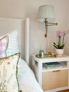 a bedroom with a bed, nightstand and flower pot on the side table next to it