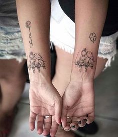 two people holding hands with tattoos on them