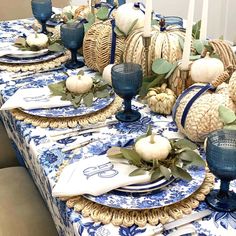 a blue and white table setting with pumpkins