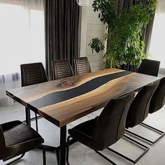 a dining table with chairs around it in front of a window and potted plant