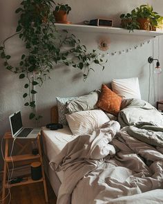 an unmade bed with plants on the headboard and pillows in front of it