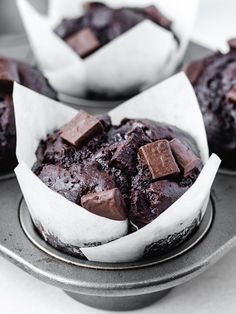 three chocolate muffins sitting on top of a metal pan next to each other