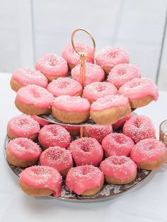 two tiered trays filled with pink donuts on top of a white table