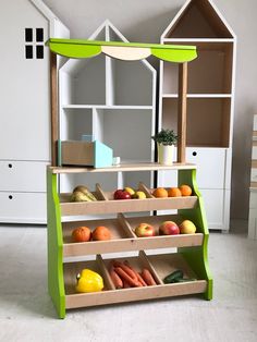 a green and white display case filled with fruits and vegetables next to a doll house