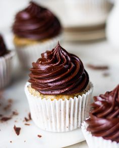 three cupcakes with chocolate frosting on top