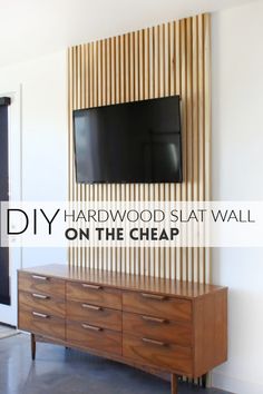 a tv mounted to the side of a wooden wall with text overlay that reads diy hardwood slat wall on the cheap