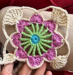 a hand is holding a crocheted flower