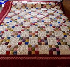 a bed with a quilt on top of it in a room next to a window