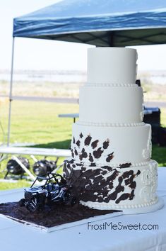 a three tiered cake sitting on top of a table next to a blue tent