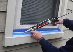 a man is using a window sealer on the side of a house