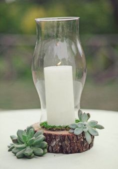 a candle is sitting in a glass vase with succulents