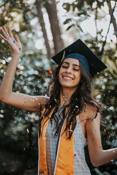 a woman wearing a graduation cap and gown throwing confetti in the air with her hands