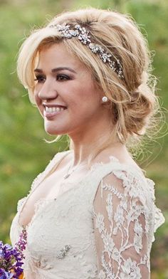 a woman in a wedding dress holding a bouquet of flowers and smiling at the camera