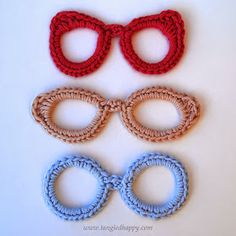 three pairs of eyeglasses and two rings on a white surface with red, blue, and brown beads