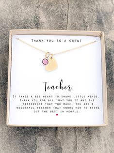 a thank you to a great teacher necklace in a gift box on a stone surface