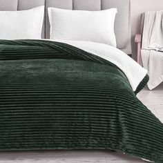 a bed with green bedspread and white pillows