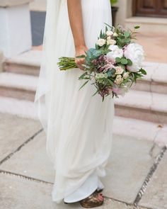 a woman in white dress holding a bridal bouquet