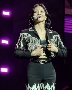 a woman in black and white outfit on stage holding a microphone with her mouth open