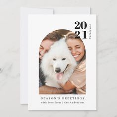 a white card with a photo of two people and a dog on the front, which says season's greetings