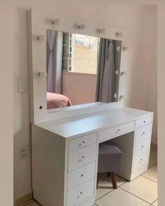 a white vanity with drawers and a mirror on the wall next to a bed in a room