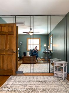 a woman is sitting in the living room looking at her reflection in the mirrored door