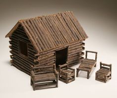 an old log cabin with chairs and a chair next to it on a white surface