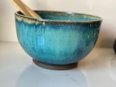 a blue bowl with chopsticks in it on a white countertop next to a black object