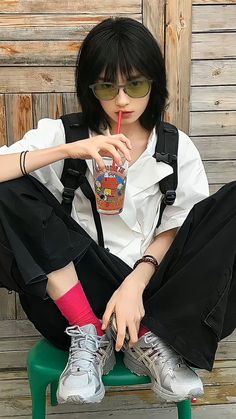 a person sitting on a green chair with a drink in their hand and wearing sunglasses