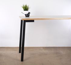 a table with a potted plant sitting on it's top next to a white wall