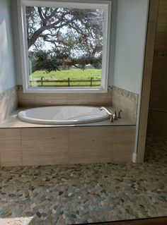 a bath tub sitting under a window in a bathroom