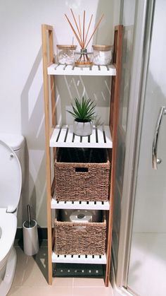 a bathroom with a toilet, shower and shelf filled with baskets next to the toilet