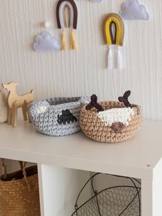 two crocheted baskets sitting on top of a white table next to each other