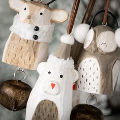 three wooden ornaments hanging from a tree with white and brown decorations on it's sides