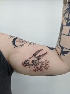 a person with a tattoo on their arm holding up a clock and an animal skull