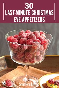 a glass bowl filled with raspberries on top of a wooden table next to a plate