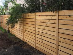 a wooden fence with plants growing on the top and bottom part, along side it