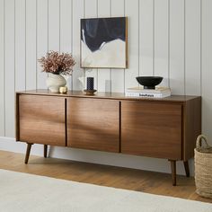 a wooden cabinet with two vases on top of it next to a white rug