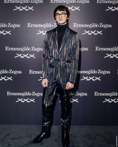 a man in a suit and tie standing on a red carpet with the words ermeneglio zegano