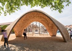 a person standing under a tree in front of a large structure that looks like an arch