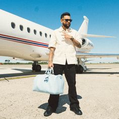 a man holding a bag standing in front of an airplane