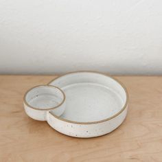 two white dishes sitting on top of a wooden table