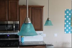 two blue lights hanging from a kitchen ceiling over a stove top oven and microwave in a home