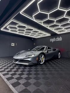 a silver sports car is parked in a garage with black and white checkered flooring