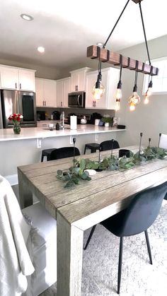 a dining room table with chairs and lights hanging from it's centerpieces