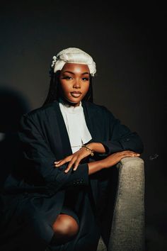 a woman sitting on top of a chair wearing a black jacket and white headband