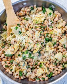 a pan filled with beans, artichokes and parmesan cheese on top