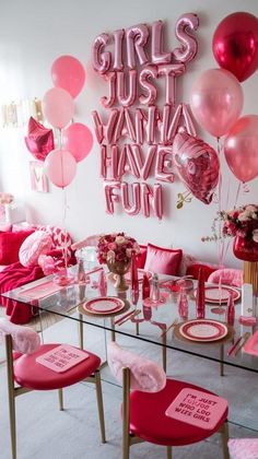 a table with pink chairs and balloons on the wall