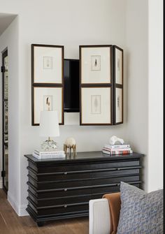 a black dresser with pictures on the wall above it