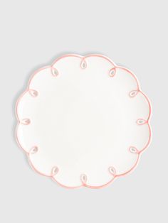 a white plate with pink trim on the edge and an oval design in the middle